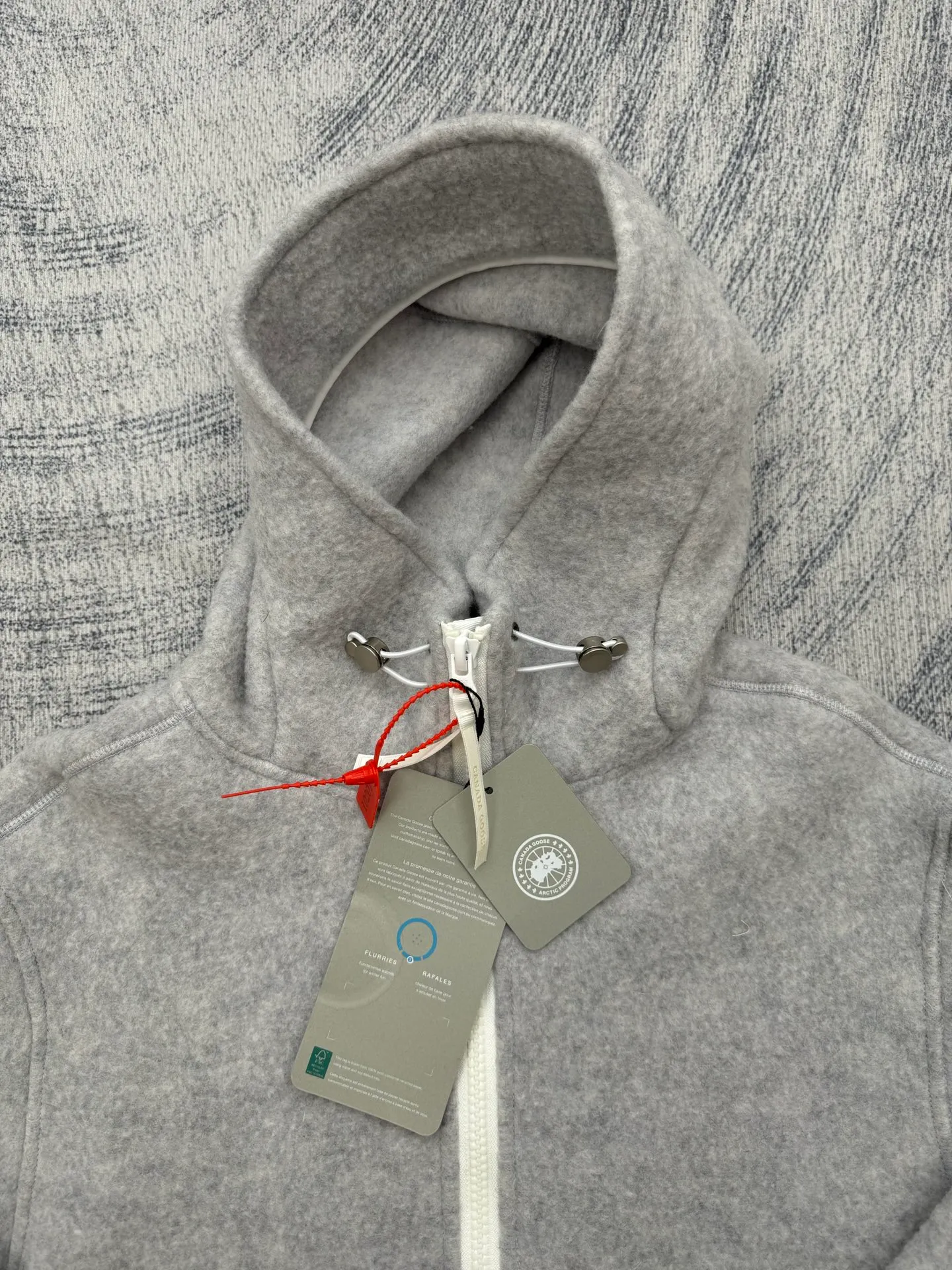 P810 Canada Goos Fleece Badge Hooded Jacket SIZE S/M/L/XL The fabric is made of wool as the main body, with a very small amount of spandex and polyester fiber blended into the wool fleece fabric. The sleeves and hem are closed with 2×2 ribbing. Its strong elasticity can closely fit wrists and waists of different thicknesses, forming an effective 'seal' to prevent cold wind from blowing back. It can still maintain its original shape after repeated stretching and use, and is not easy to loose and deform. And the ribbed cuffs can convey a sense of design and enhance the visual beauty.